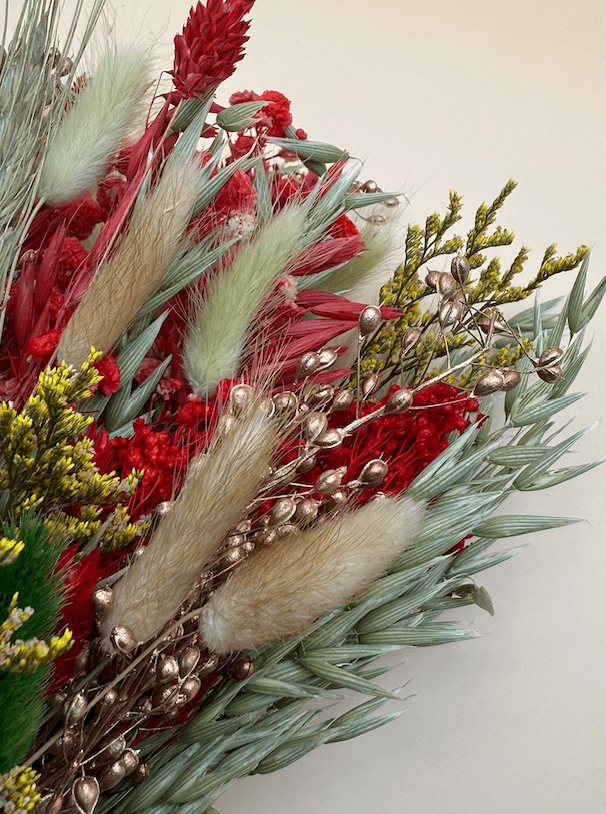 Bouquet of red flowers, greenery, and decorative elements on a light background