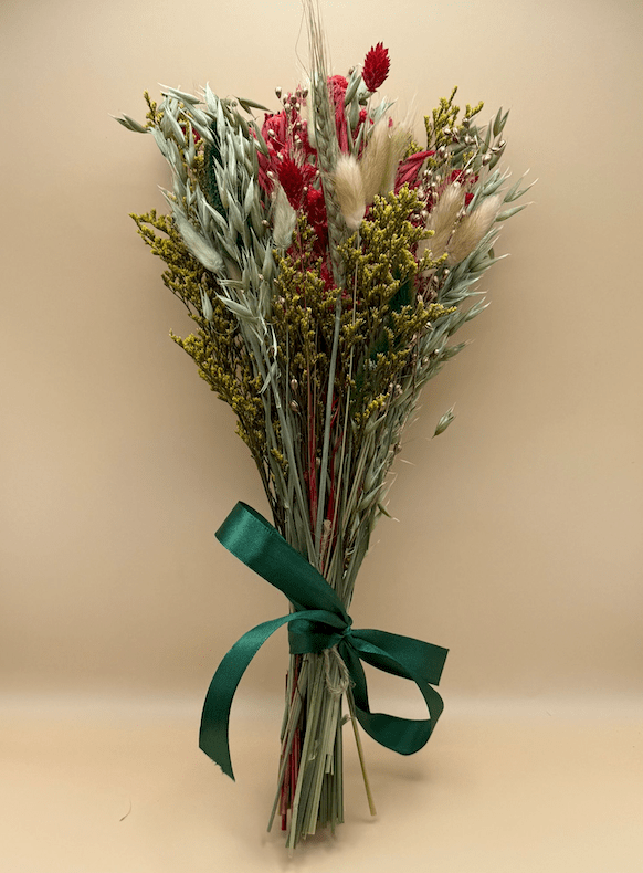 Bouquet of dried flowers with a green ribbon on a beige background