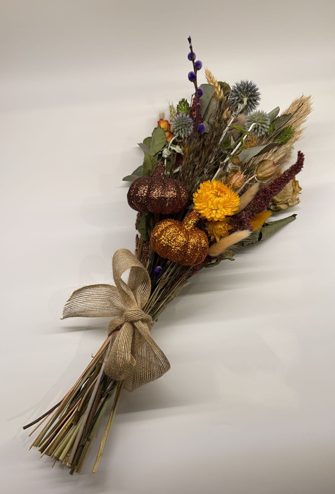 Bouquet of dried flowers with pumpkins and a bow on a white background