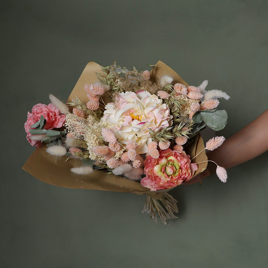 Bouquet of flowers held by a hand against a dark background