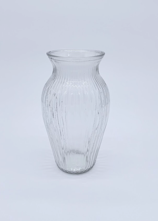 Clear glass vase with ribbed design on a wooden surface and white background