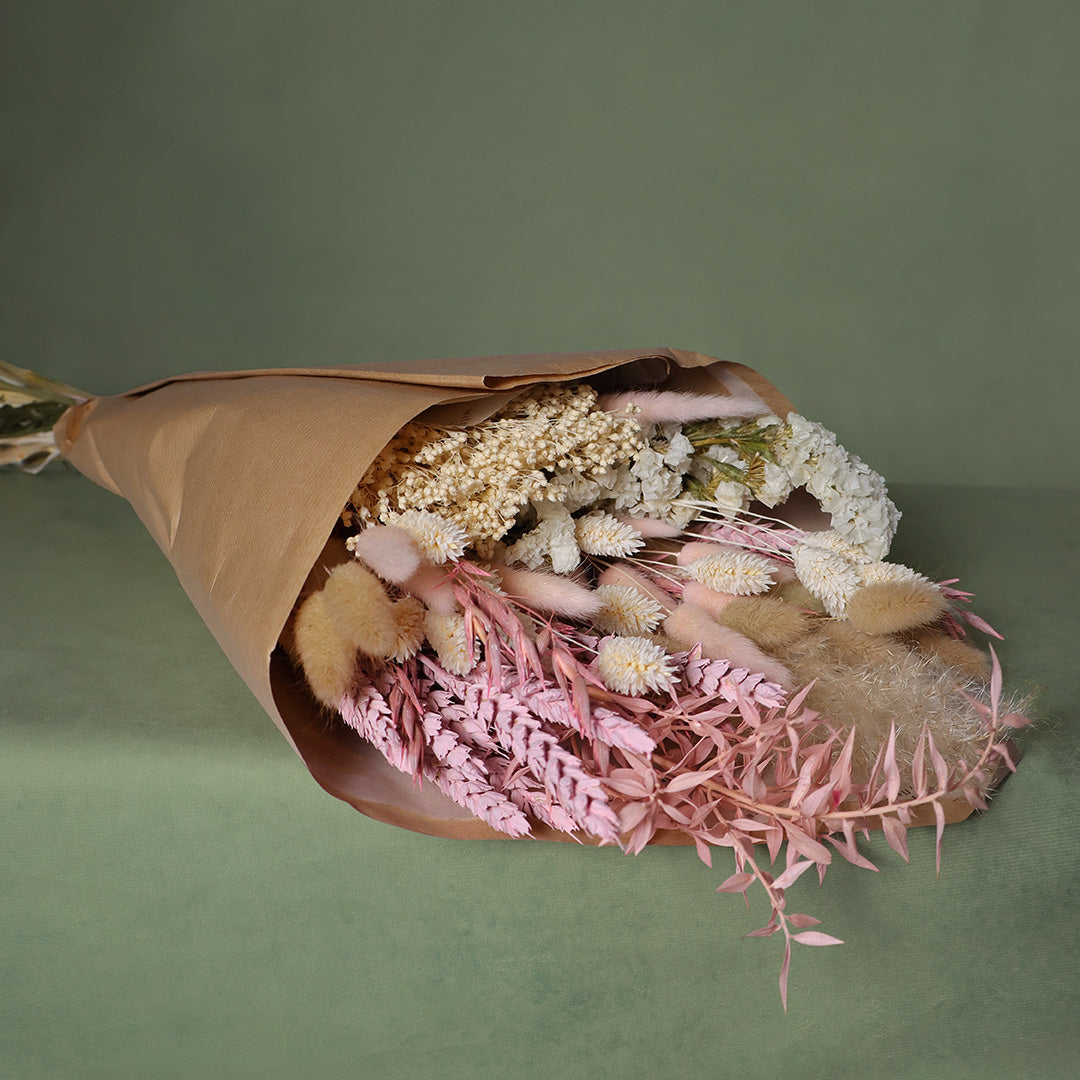 Bouquet of dried flowers wrapped in brown paper on a green background