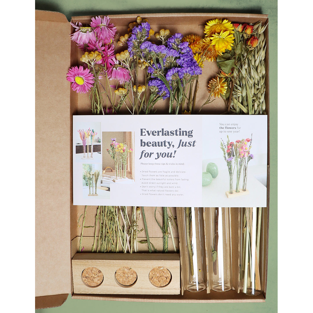 Floral arrangement kit with flowers and packaging on a green background