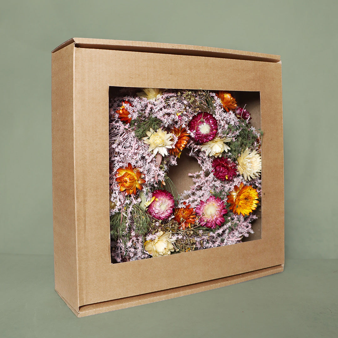 Floral wreath in a cardboard box on a green background