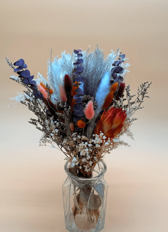 Bouquet of dried flowers in a glass vase on a blurred background