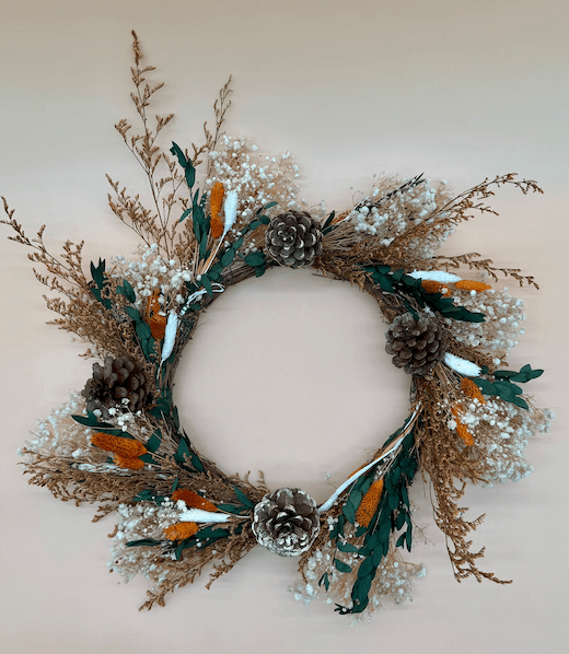 Decorative wreath with pinecones and dried foliage on a plain background