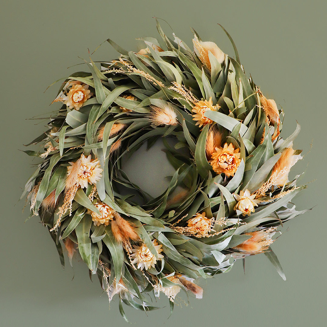Decorative wreath with green leaves and orange flowers on a gray background