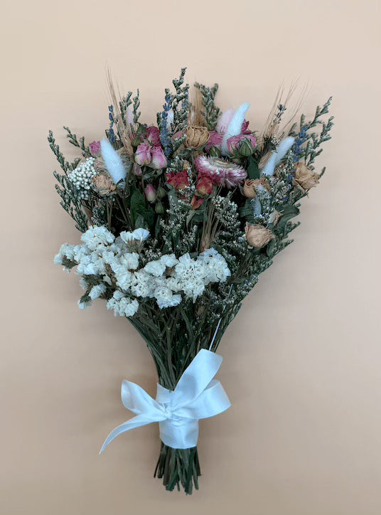 Bouquet of dried flowers with a white ribbon on a beige background