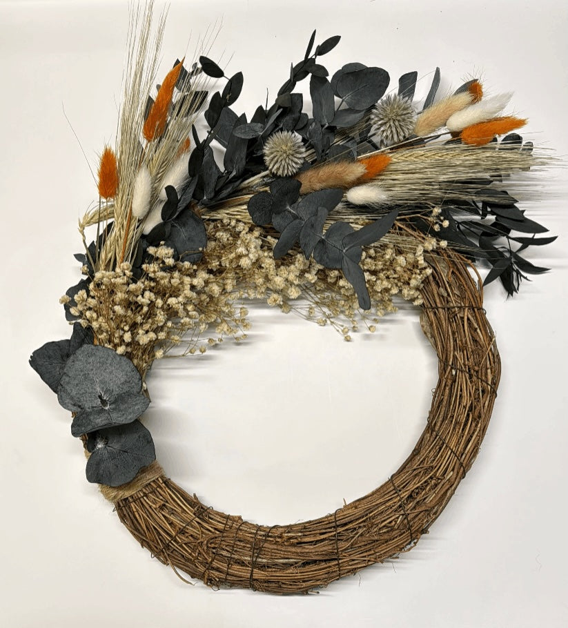 Decorative wreath with dried flowers and leaves on a white background
