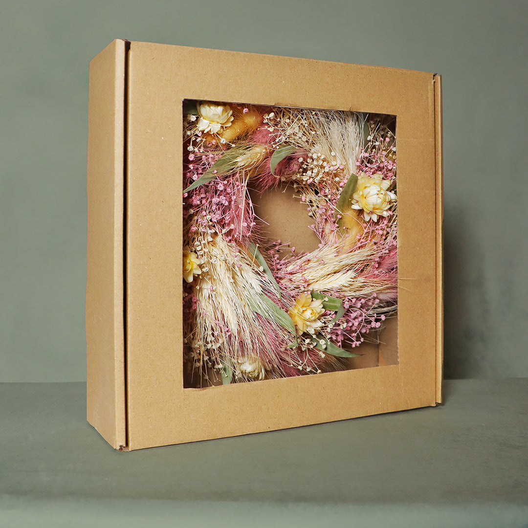 Floral wreath inside a cardboard box on a gray background
