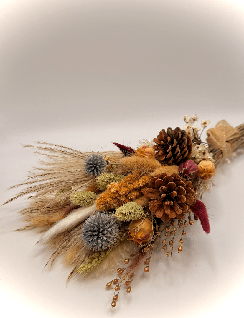 Dried floral arrangement with pinecones and herbs on a light background