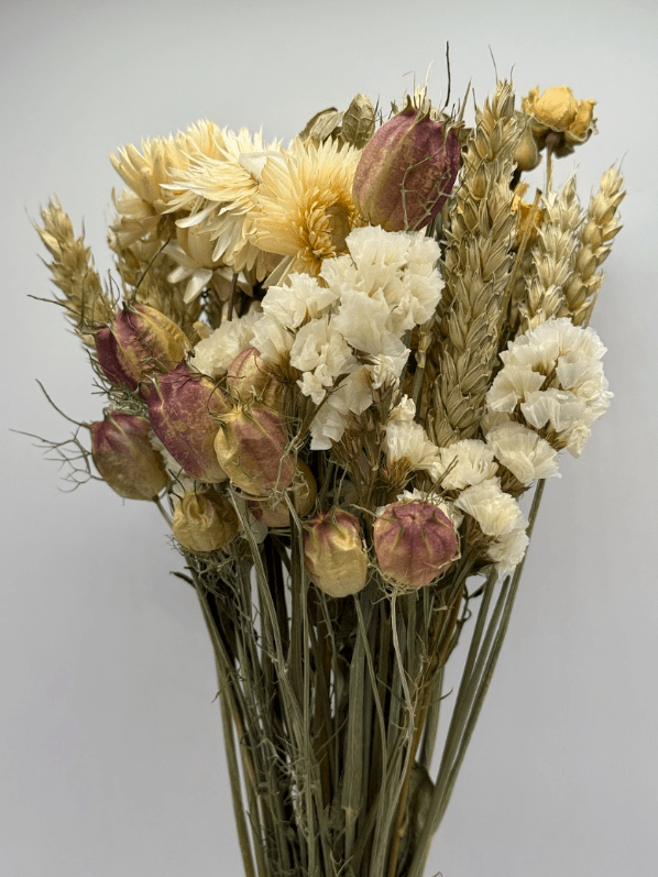 Bouquet of dried flowers with yellow, white, and purple hues on a gray background