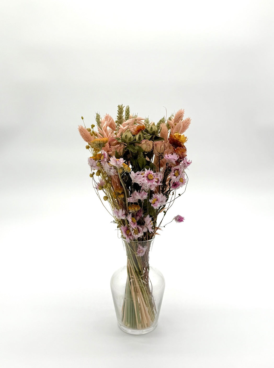Bouquet of dried flowers in a clear vase on a white background