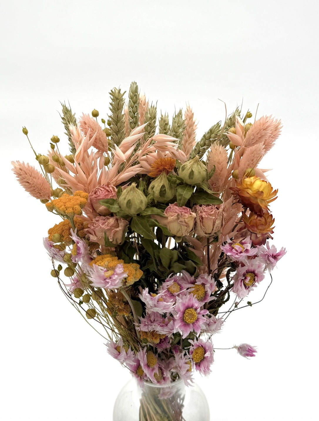 Bouquet of dried flowers in a clear vase on a white background