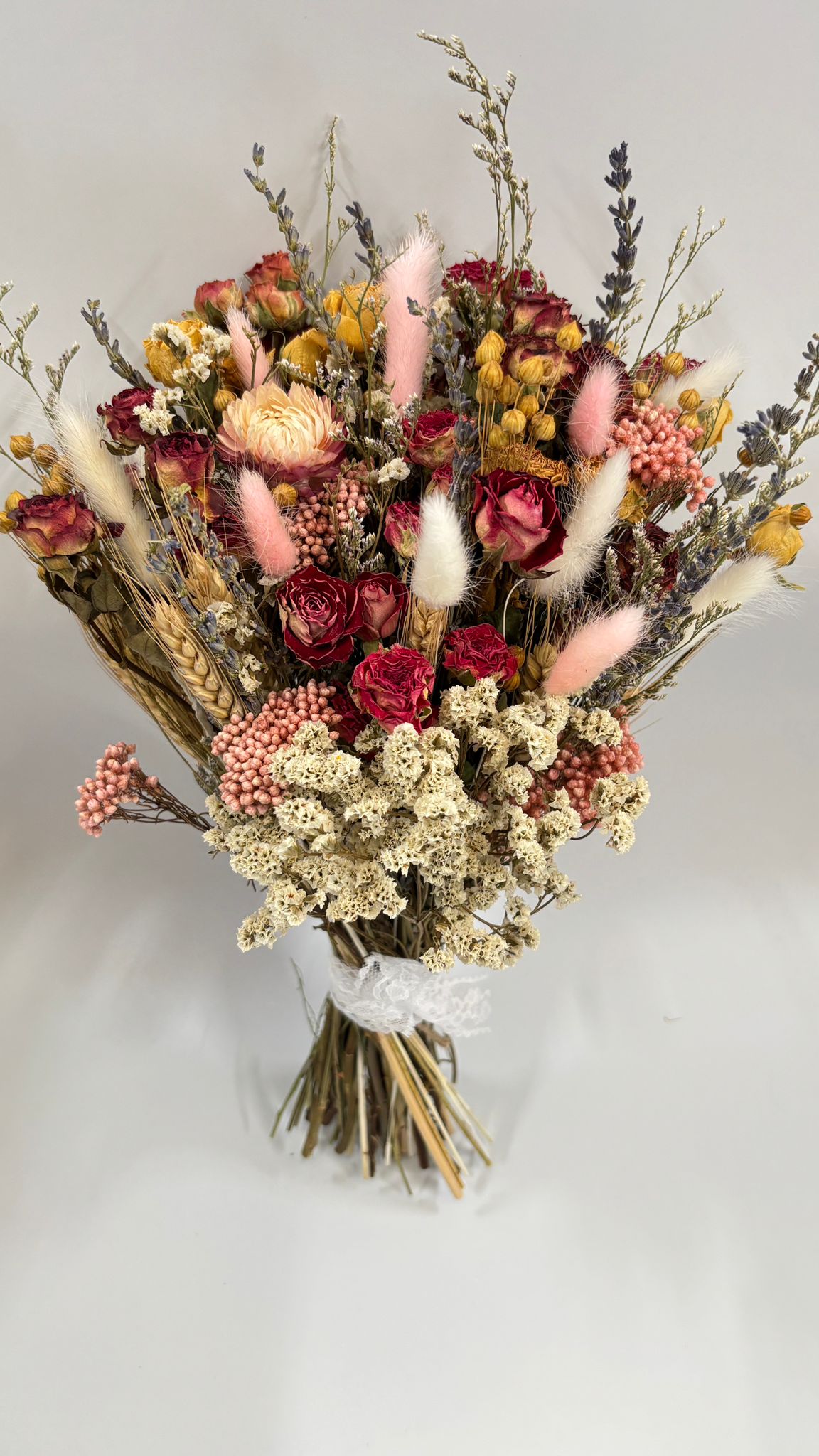 Bouquet of dried flowers with pink and red tones on a light gray background
