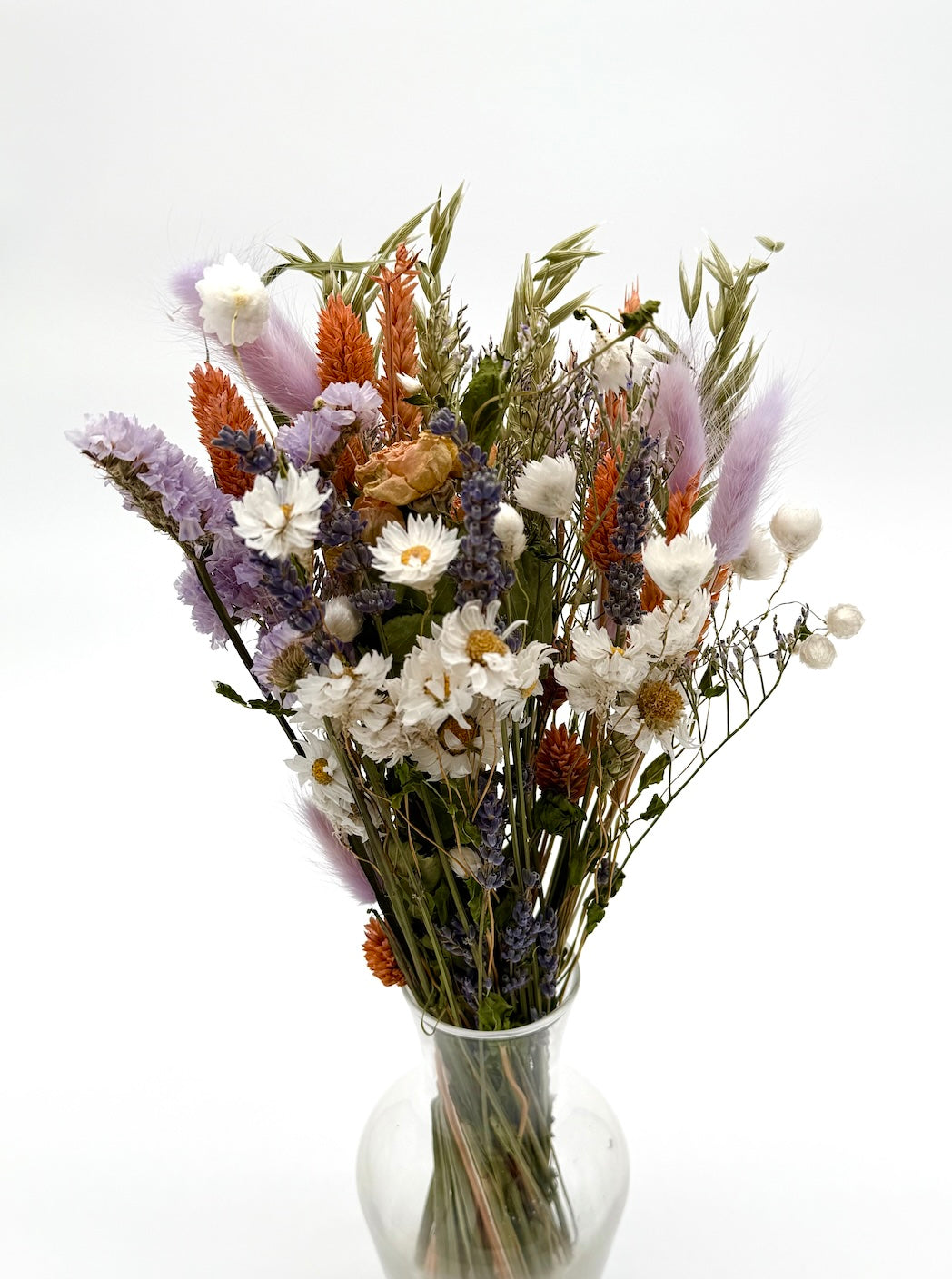 Bouquet of dried flowers in a clear vase on a white background