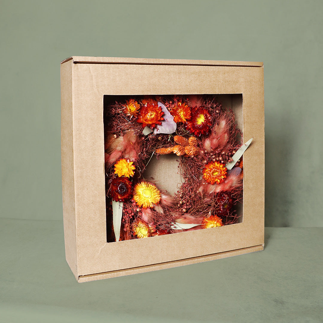 Decorative wreath with autumnal elements in a cardboard box on a green background