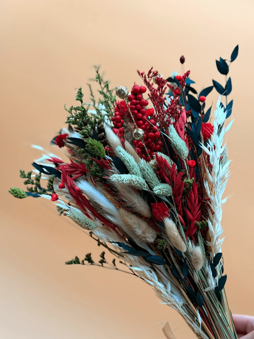 Bouquet of dried flowers with red and green colors on a beige background