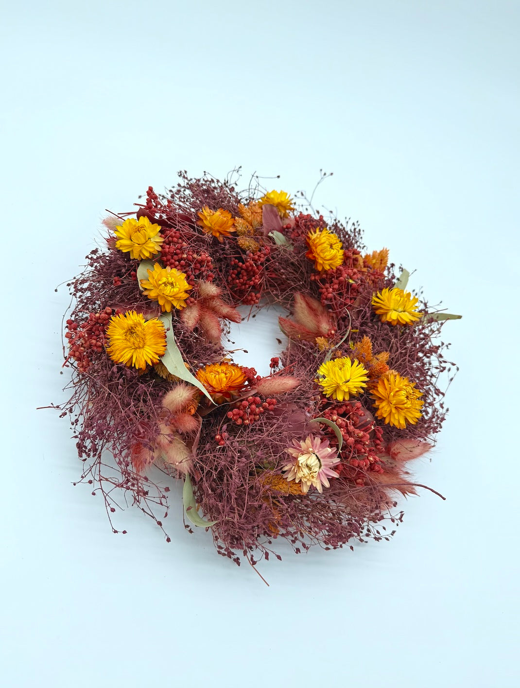 Decorative wreath with autumnal colors on a light blue background