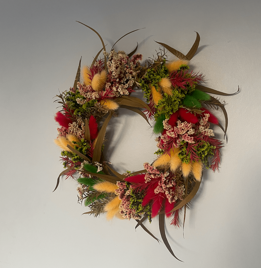 Decorative wreath with feathers and flowers on a plain background