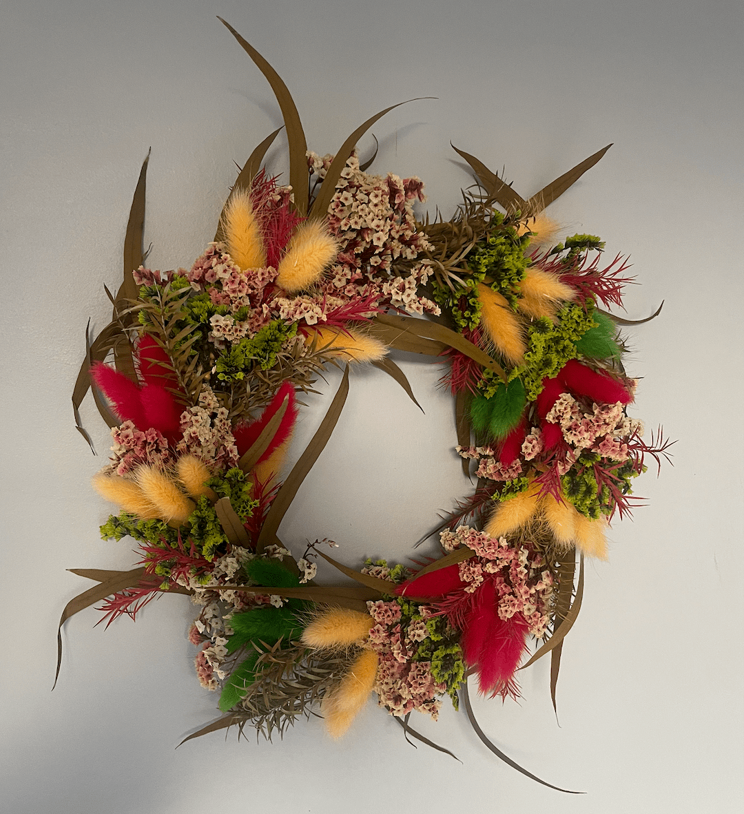Decorative wreath with colorful flowers and feathers on a white background