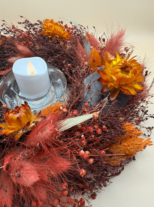Decorative wreath with candles and flowers on a white background