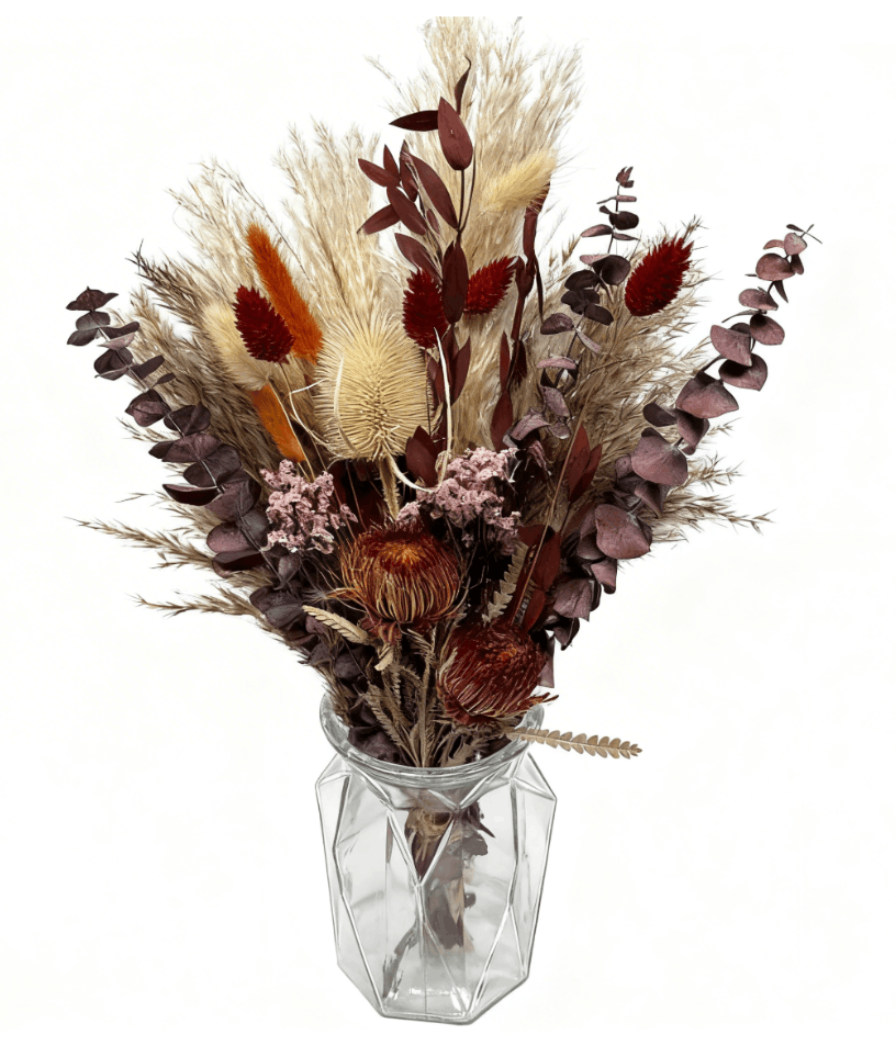 Bouquet of dried flowers in a clear glass vase on a white background
