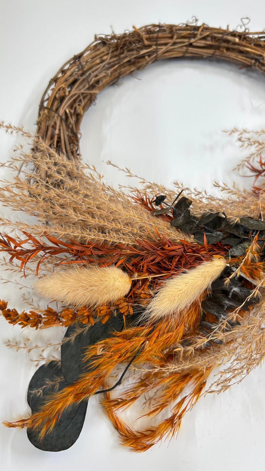 Decorative wreath with dried foliage and feathers on a white background
