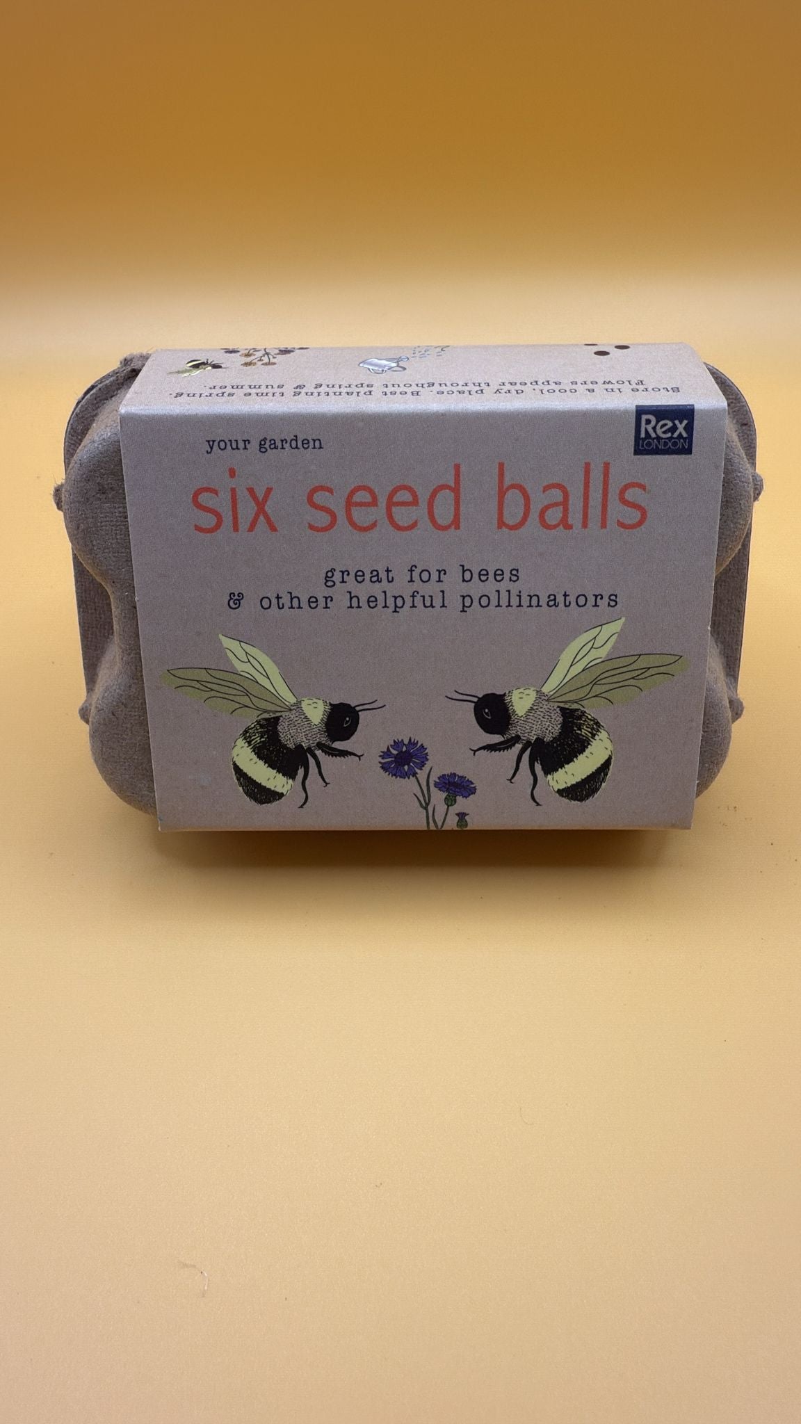 Pack of six seed balls with bee illustrations on a beige background