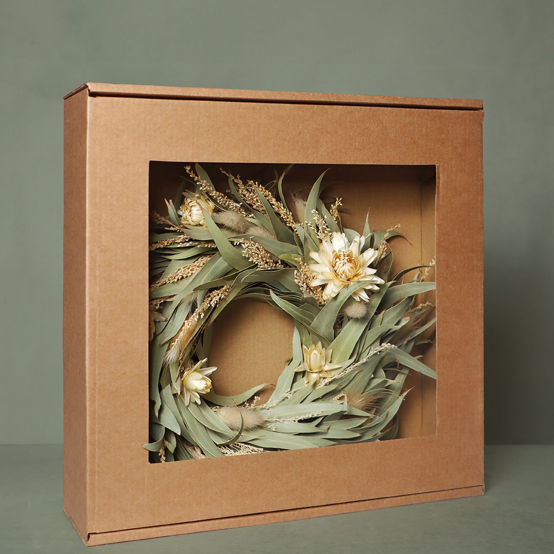 Brown gift box with a decorative wreath inside on a green background