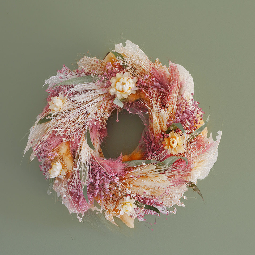 Decorative wreath with pink, orange, and white flowers on a green background