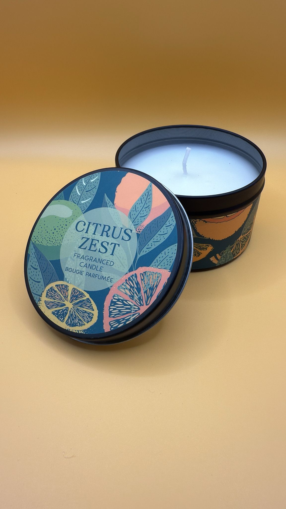 Candle in a tin with 'Citrus Zest' label on a beige background