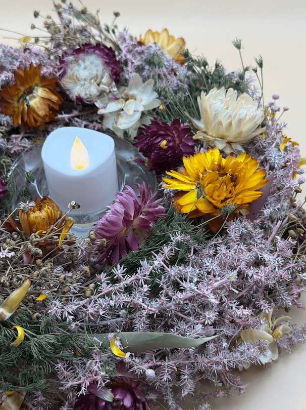 Decorative wreath with flowers and a candle on a white background