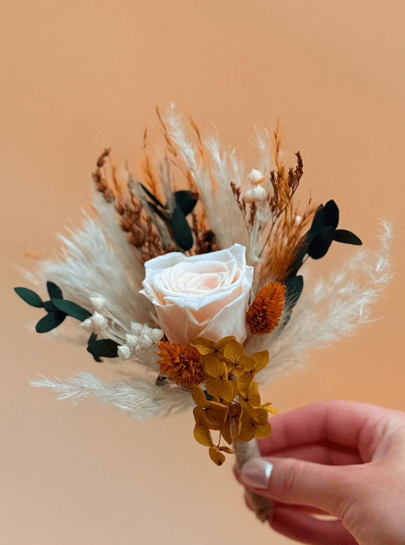 Hand holding a small bouquet of flowers against an orange background