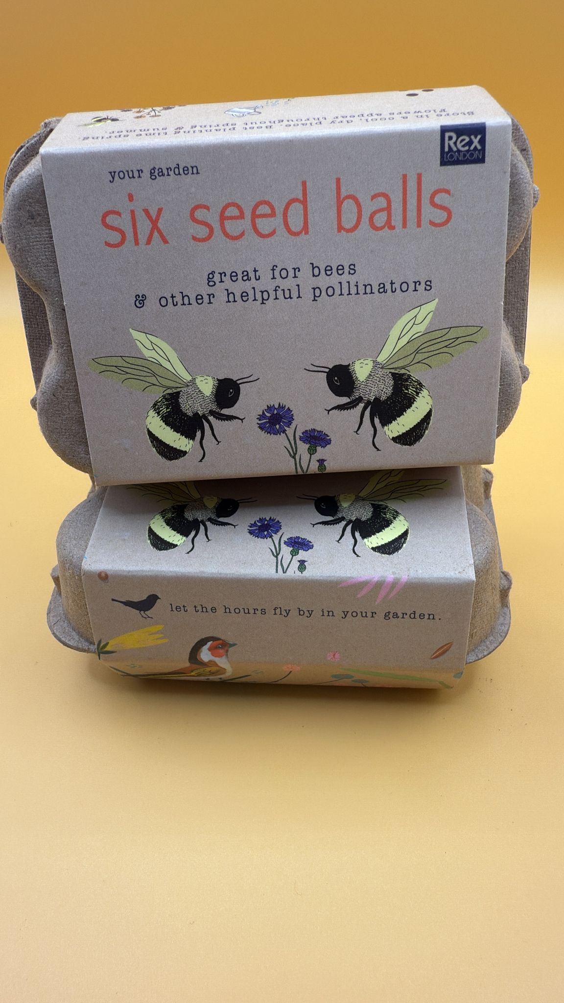 Two boxes of six seed balls with bee illustrations on a yellow background