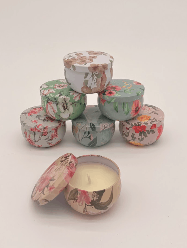 Candle in a floral-patterned tin on a beige surface with a light background