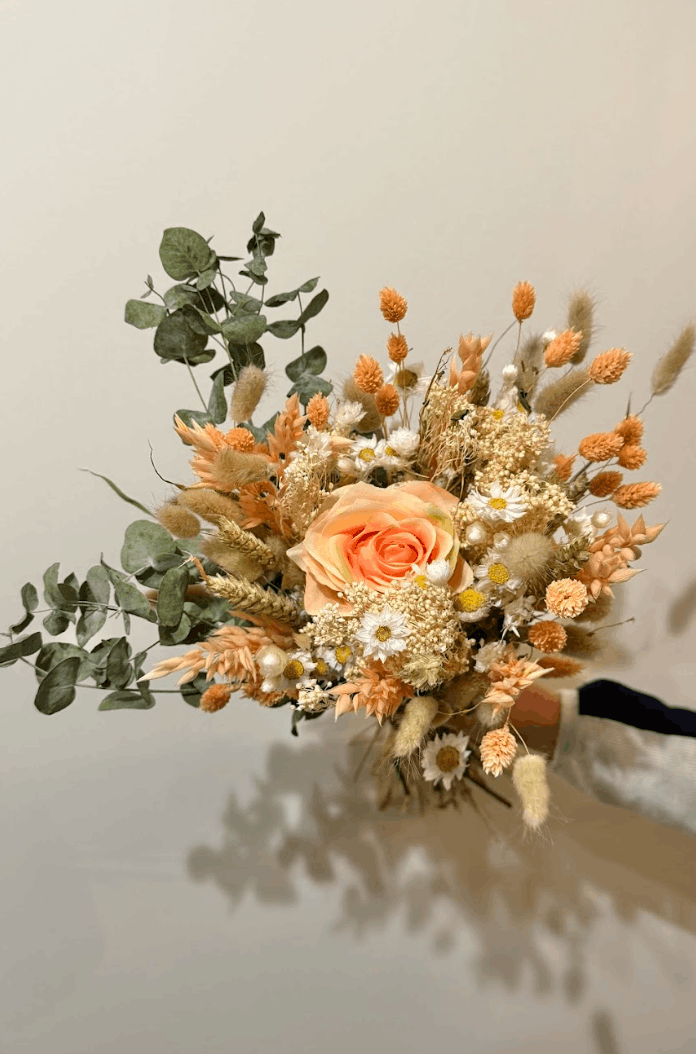 Bouquet of dried flowers with orange and green elements on a neutral background