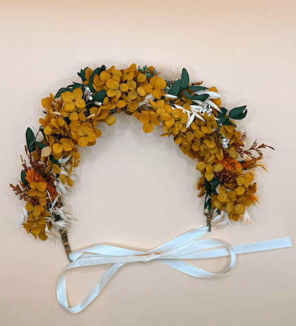 Floral wreath with yellow flowers and green leaves on a beige background