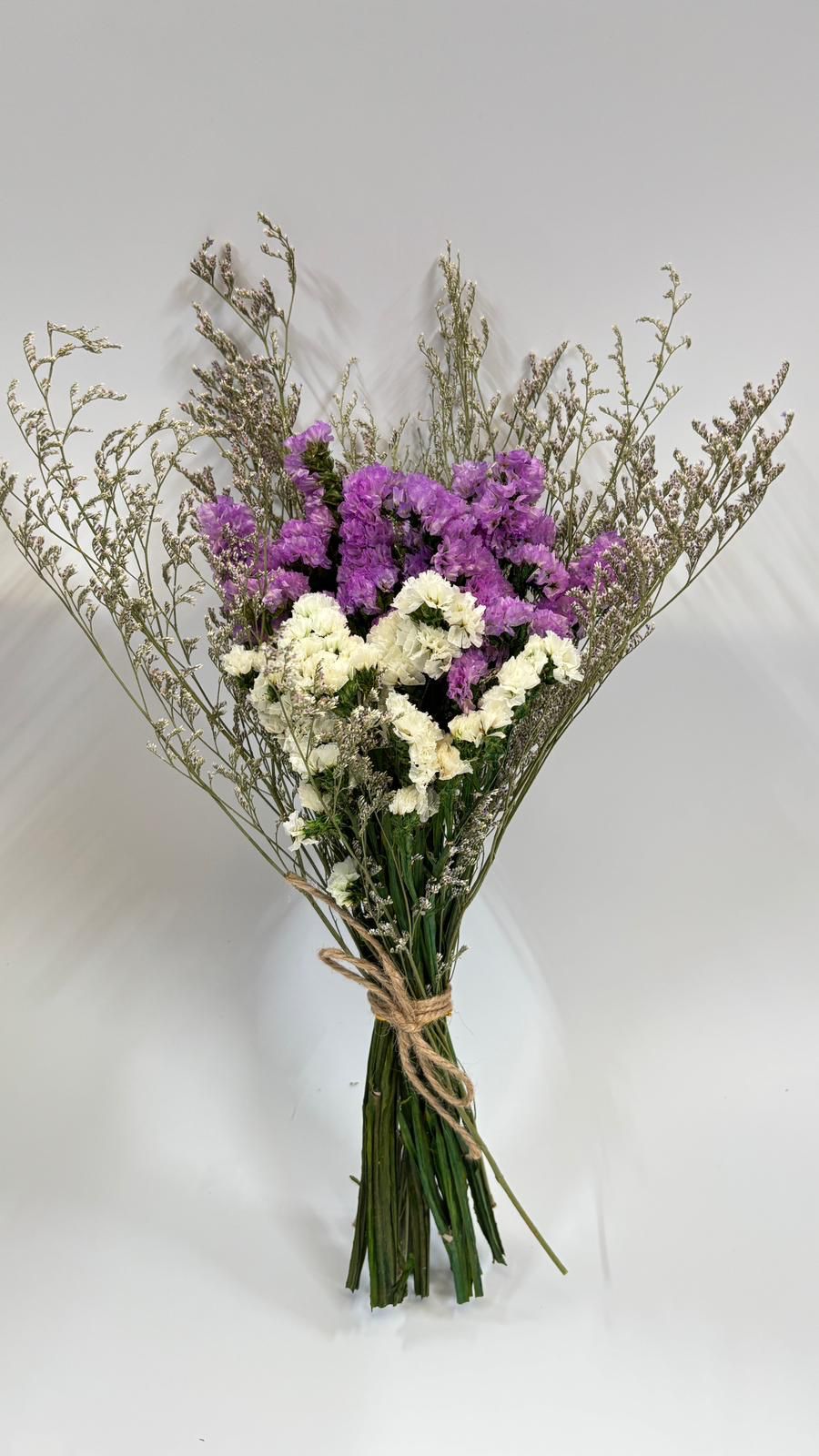 Bouquet of flowers with purple, white, and green elements on a light gray background